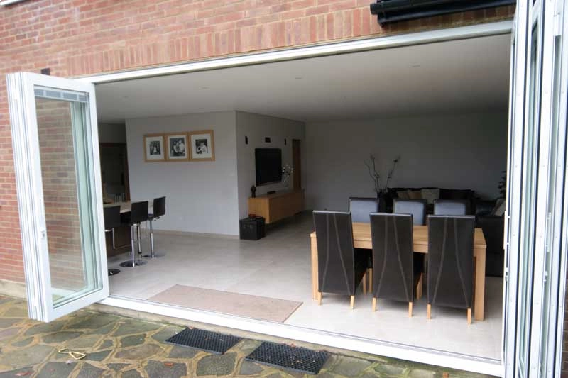 aluminium bifold doors fully opened, between a kitchen and patio in a UK home