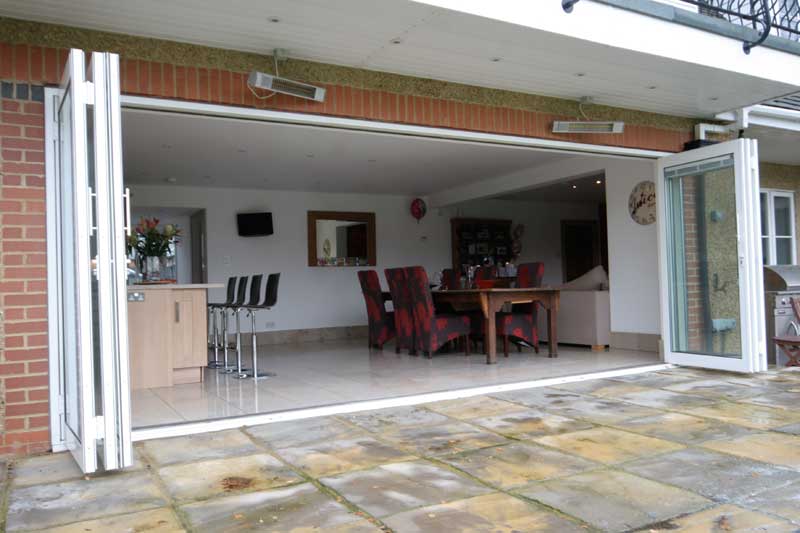 white bifold doors fully opened, between a kitchen and patio
