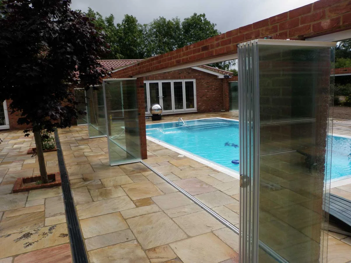 frameless glass room dividers surrounding a pool showing the open state, compactly folded away