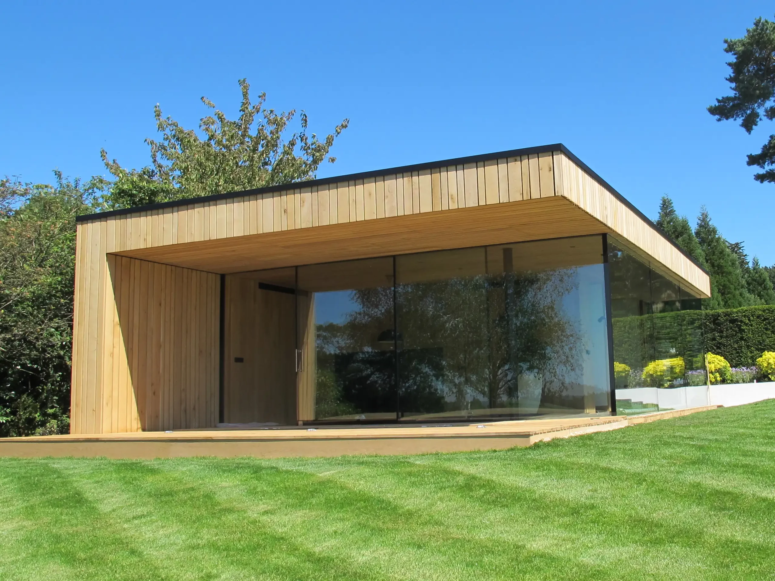 Photo of external frameless glass bifold doors, next to a garden in the UK