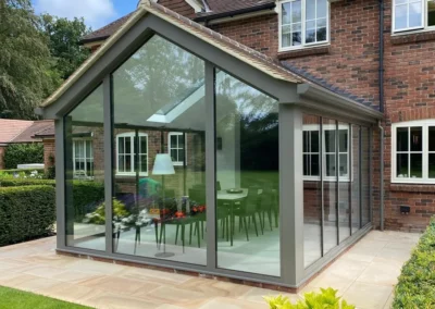 Thin profile bifold glass doors with panoramic views over a garden, UK