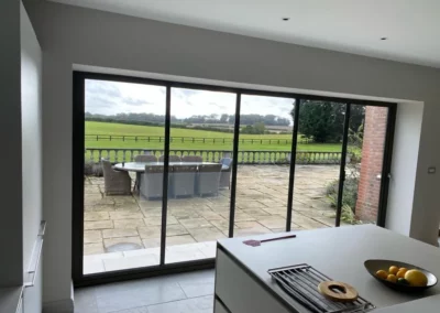 Black ultra slim sliding bifold doors looking out onto a patio from a kitchen