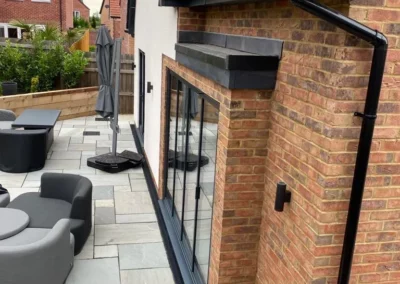 Ultra slim bifolding doors by a patio. Brick home, UK