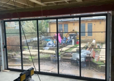 Ultra slim bifolding patio doors being installed by Vision Glass Doors looking out onto a garden