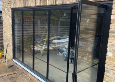 Folding sliding glass doors installation in the UK on a modern home by a patio. By Vision Glass Doors