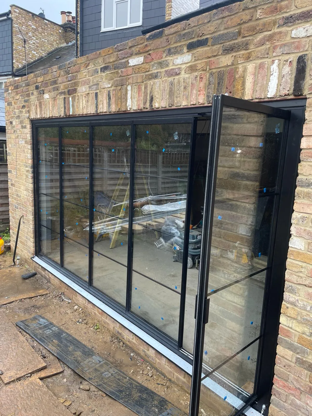 Folding sliding glass doors installation in the UK on a modern home by a patio. By Vision Glass Doors