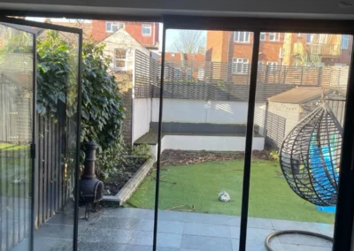 Minimal glass doors installed overlooking a patio and garden in the UK. It is partially open.