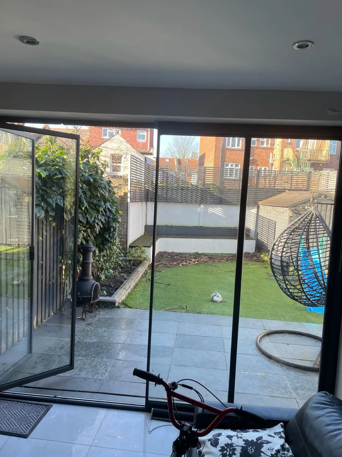 Minimal glass doors installed overlooking a patio and garden in the UK. It is partially open.