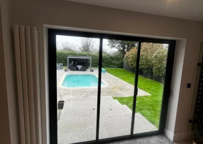Frameless glass doors, patio and pool and garden view. External