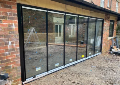Minimal glass doors installed overlooking a patio in the UK. Black minimal aluminium frames.